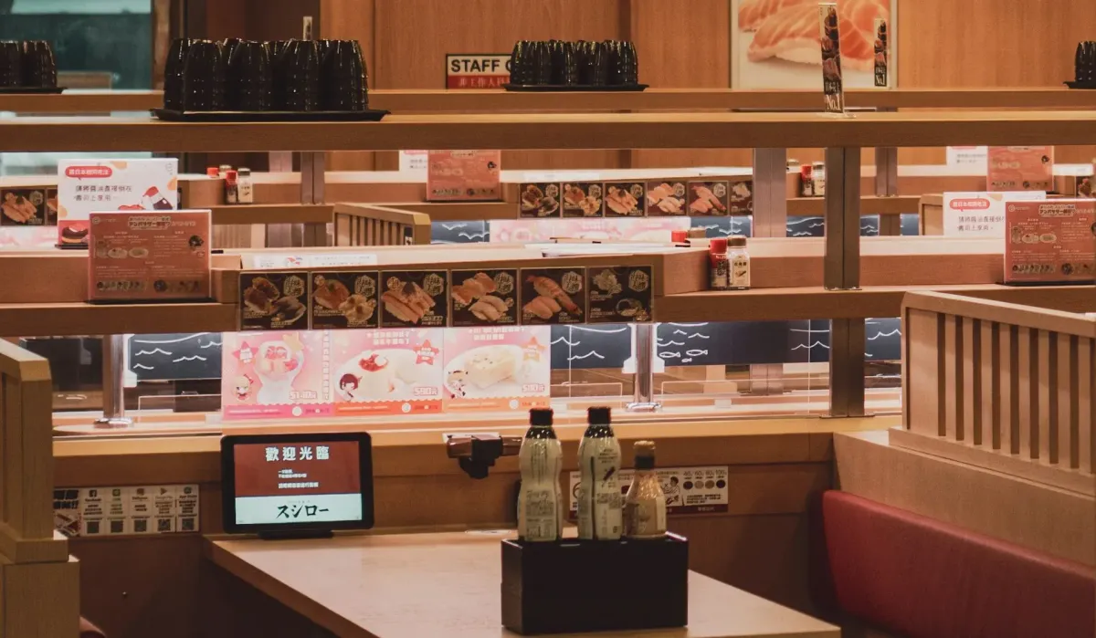 Colorful plates of sushi moving along a conveyor belt at a busy Tokyo kaiten-zushi restaurant