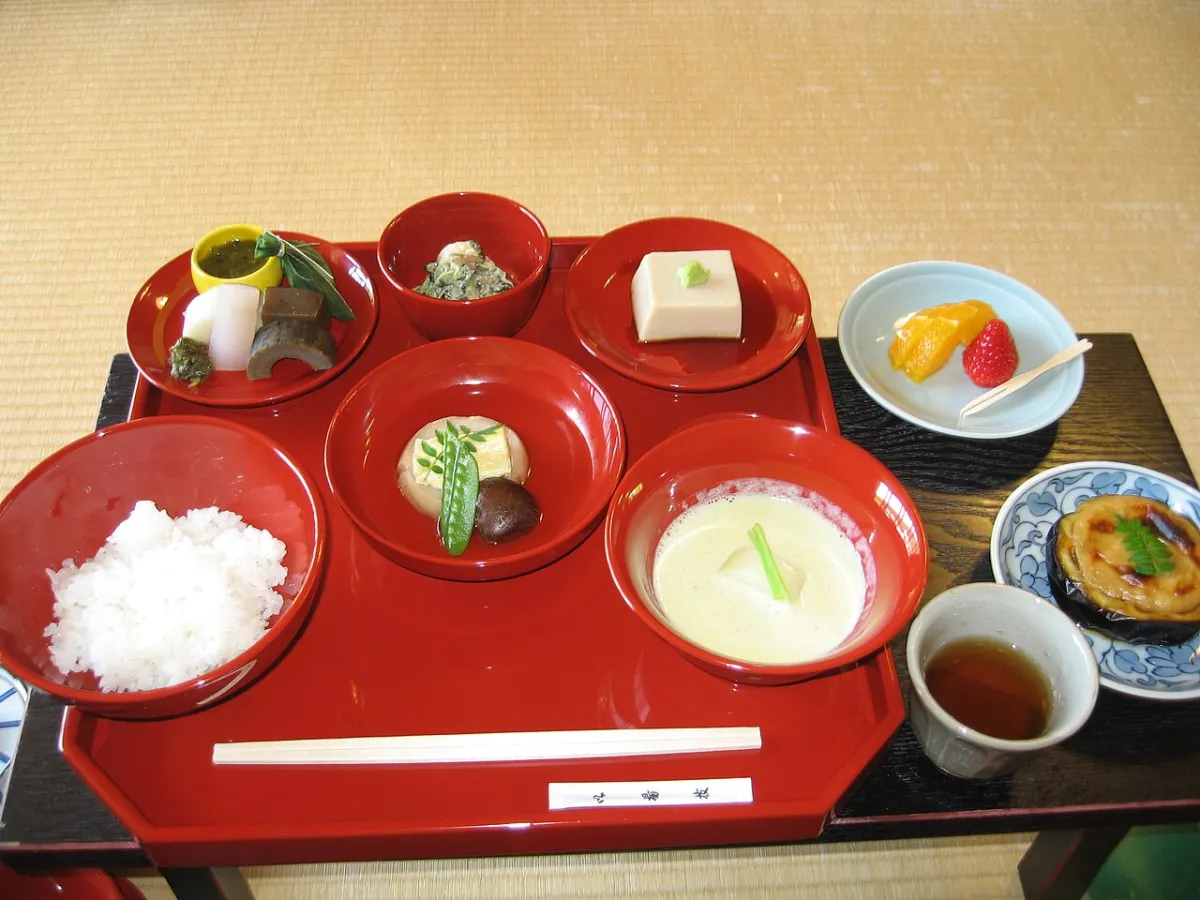 A shojin ryori set meal with rice, tofu and seasonal vegetables on a red lacquer tray
